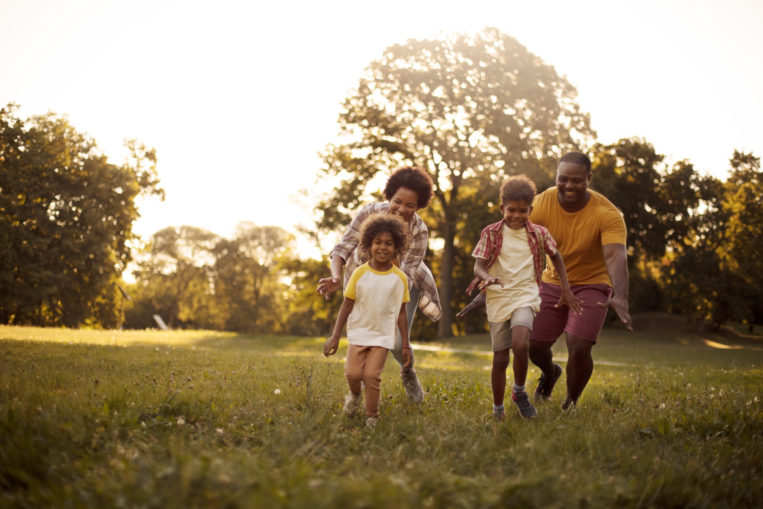 Family catching each other. African American family having fun outdoors.